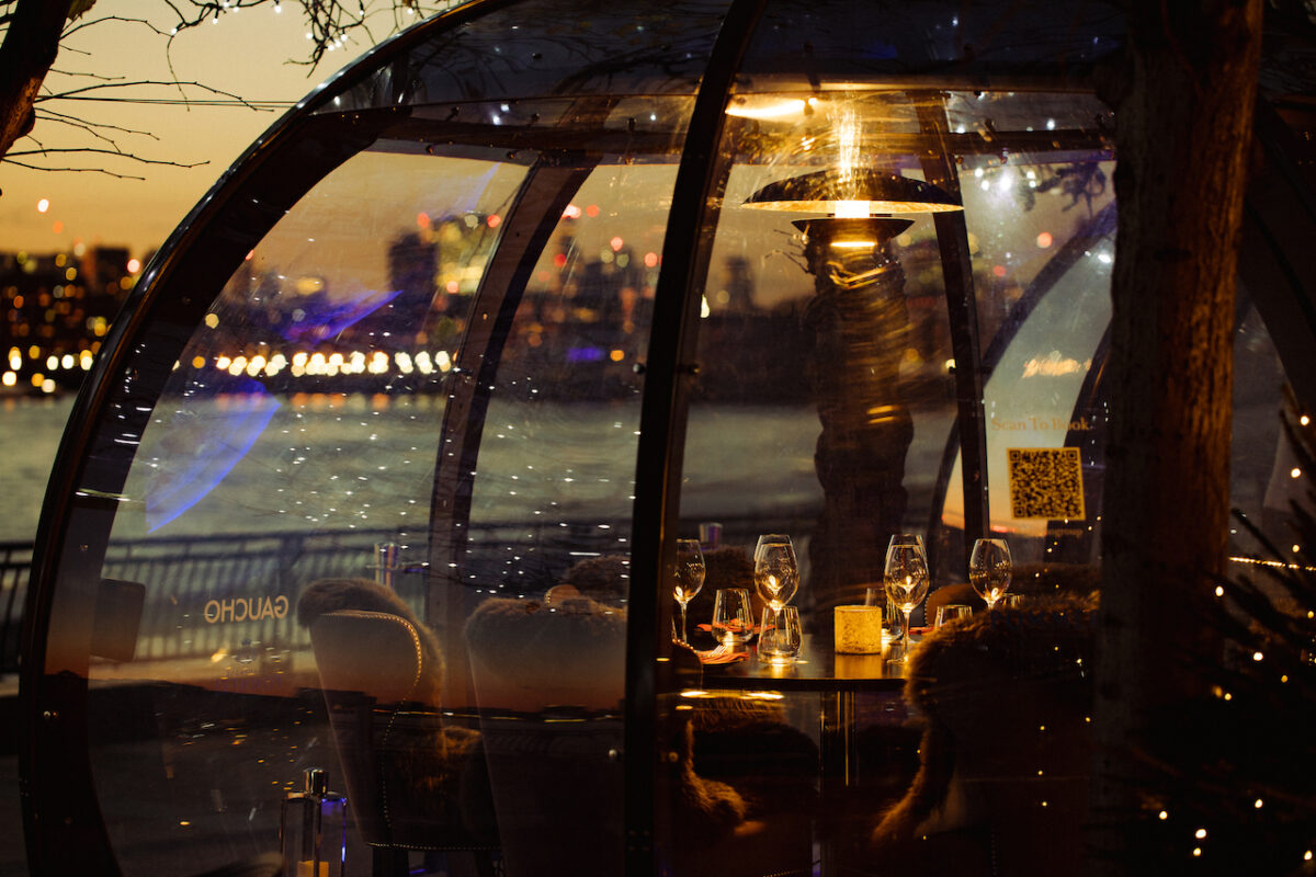 Cosy pod lit up in the dark overlooking the Thames at Gaucho Canary Wharf