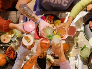 Friends saying cheers with cocktails over the table at Turtle Bay