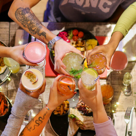 Friends saying cheers with cocktails over the table at Turtle Bay