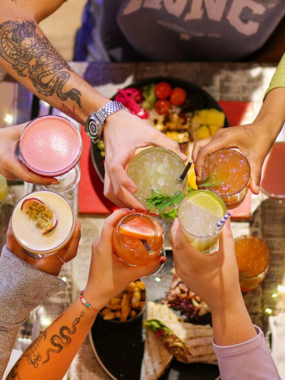 Friends saying cheers with cocktails over the table at Turtle Bay