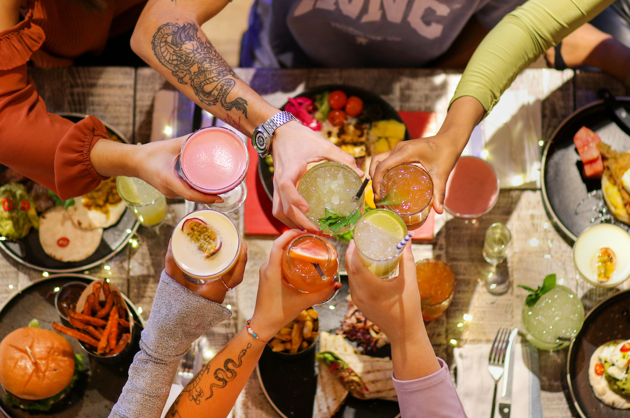 Friends saying cheers with cocktails over the table at Turtle Bay