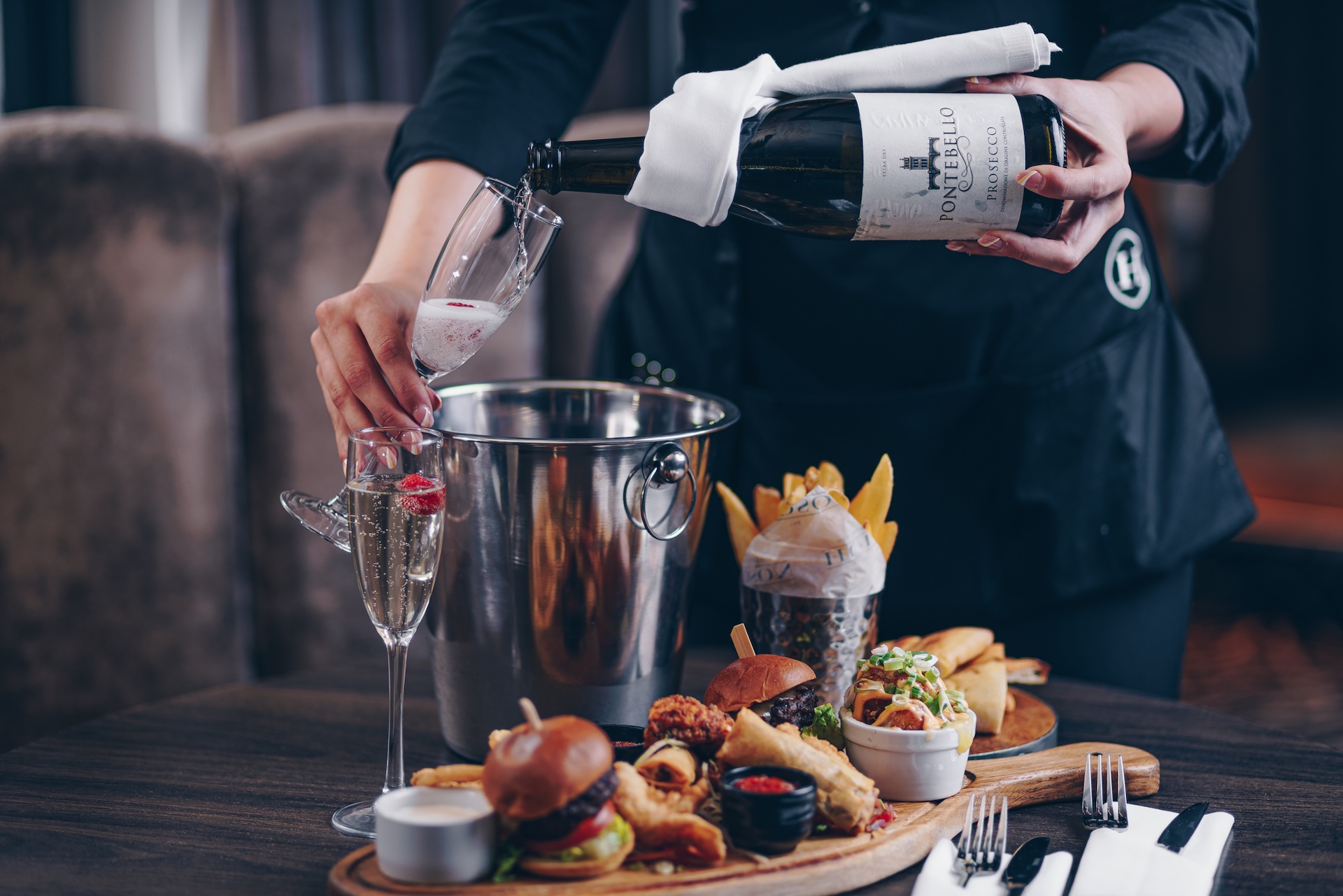 Prosecco being poured into a glass and a sharer plate of bottomless brunch items at The Hudson Newcastle