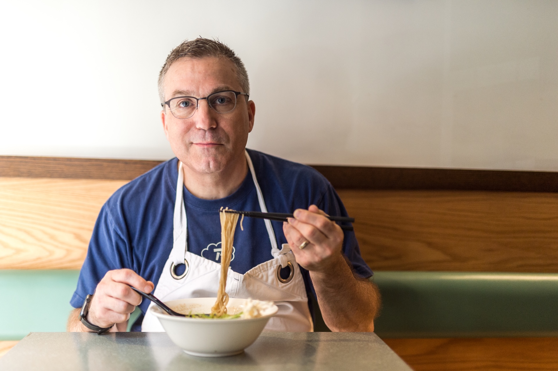 Ivan Ramen from Netflix's Chef's Table sitting at a table eating pasta