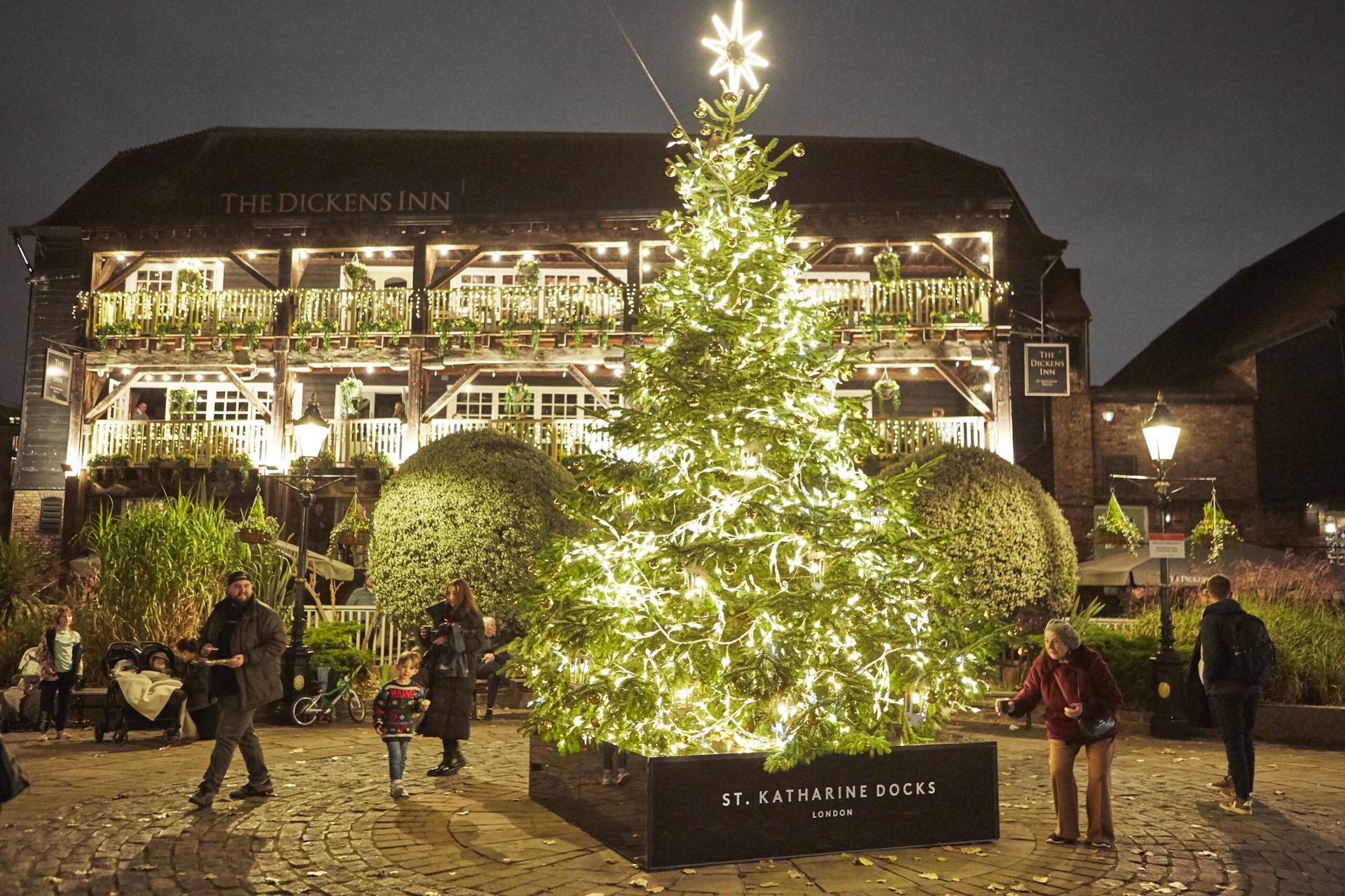 A big Christmas tree lit up with the The Dickens Inn in the background on St Katherine's Dock
