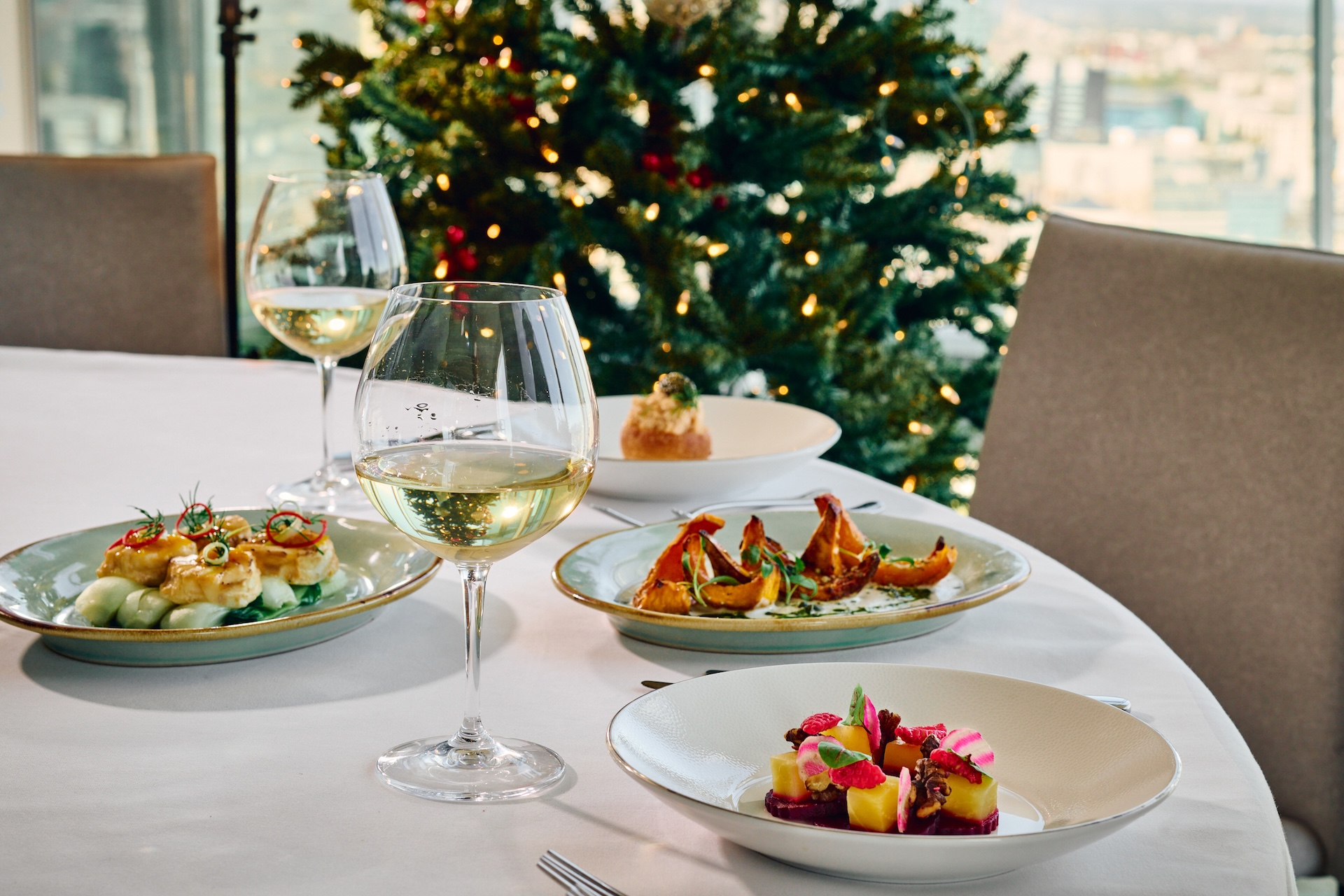 A selection of delicious small plates and two glasses of wine with christmas tree at Shangri-La The Shard