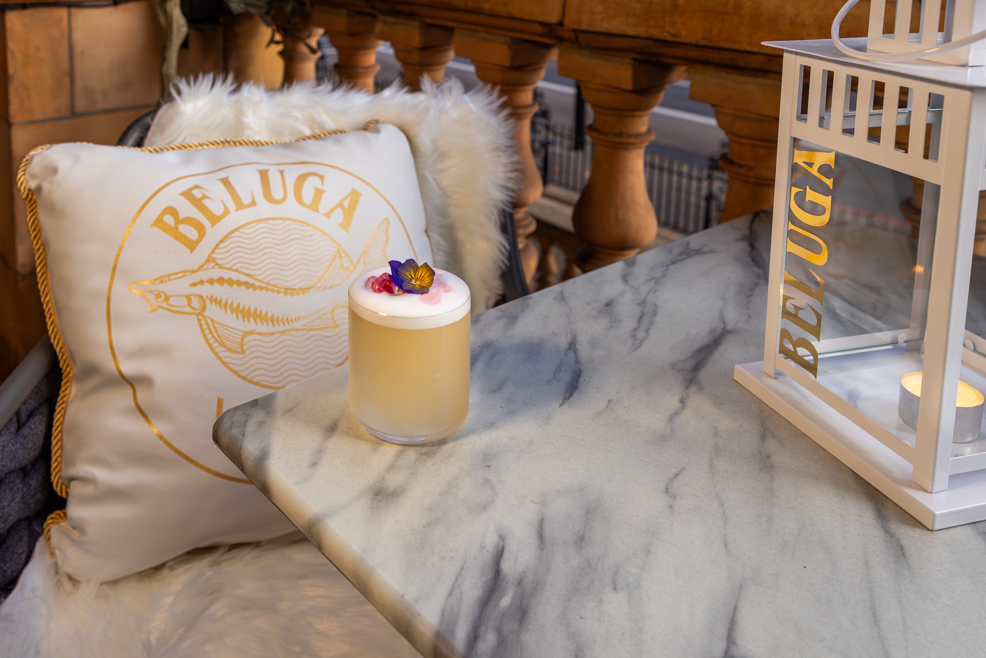 A cocktail on a marble table with a Belugla Vodka emblazoned cushion at Mirror Bar